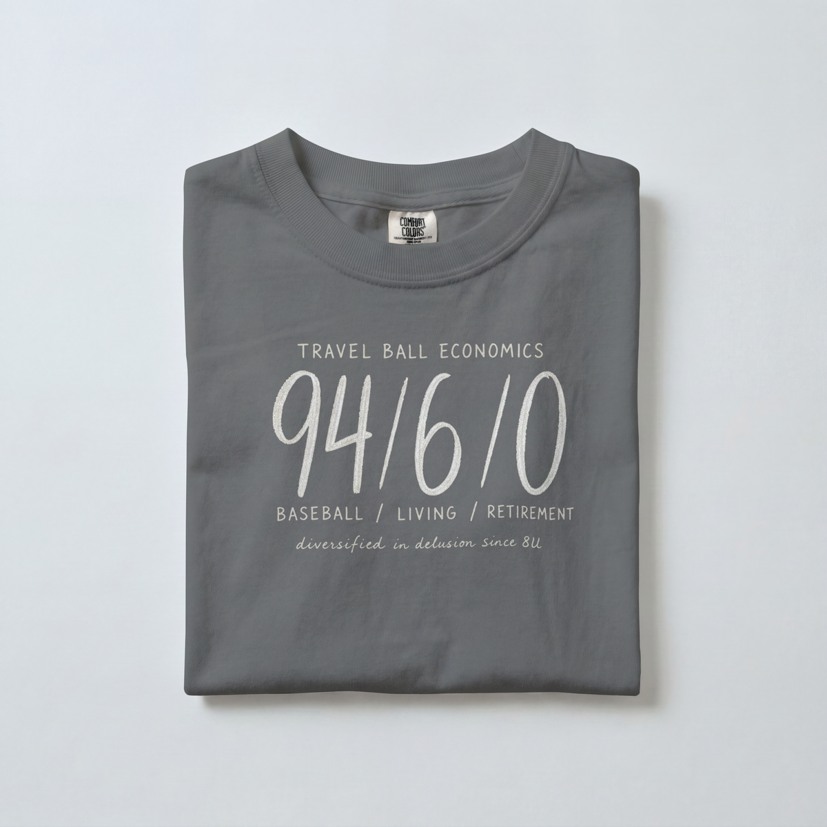 Folded Pepper Comfort Colors 1717 baseball parent shirt showing the vintage 94/6/0 design and Travel Ball Economics lettering.