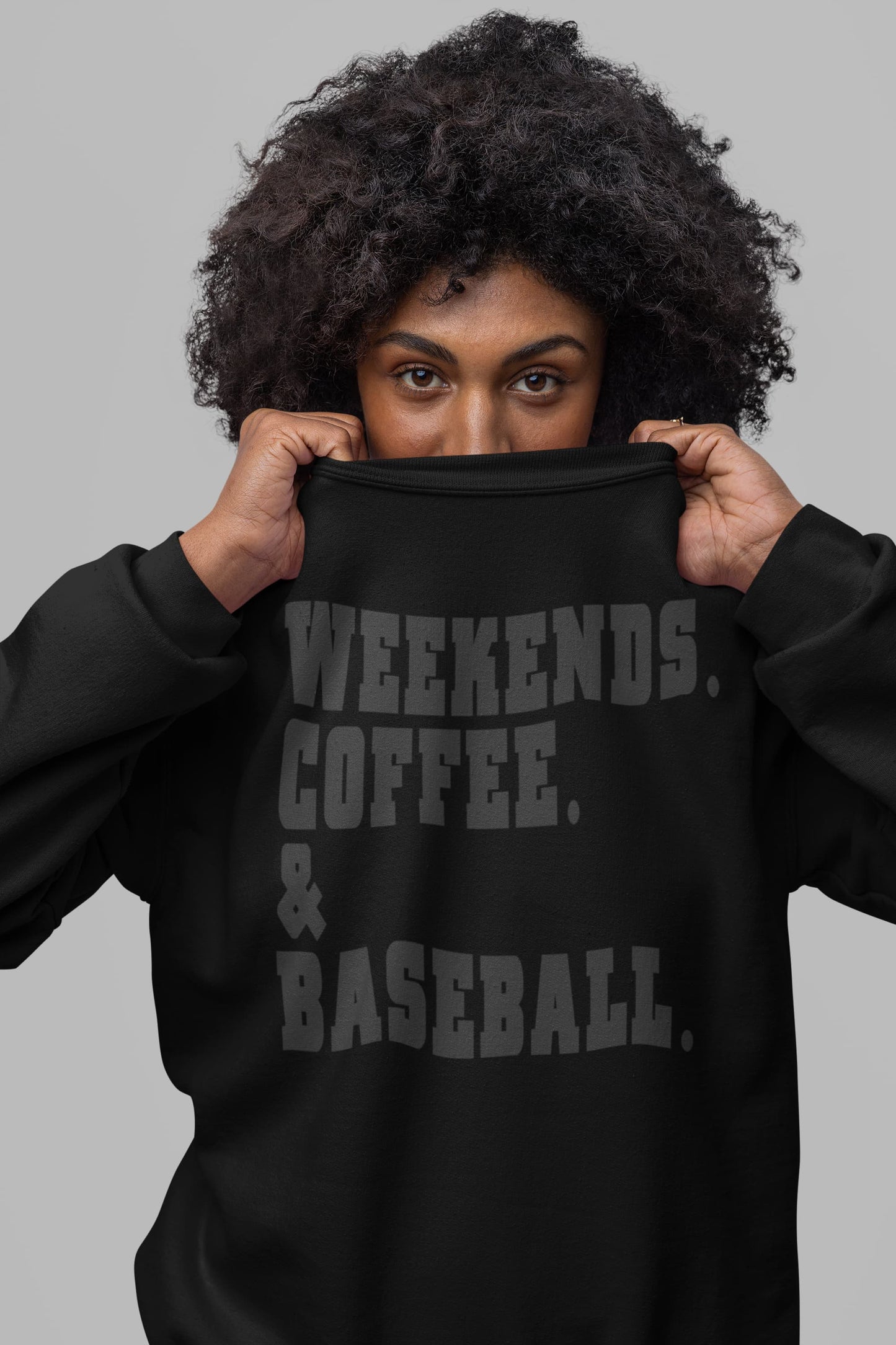 Close up of black weekends coffee baseball sweatshirt with stacked varsity text worn by woman