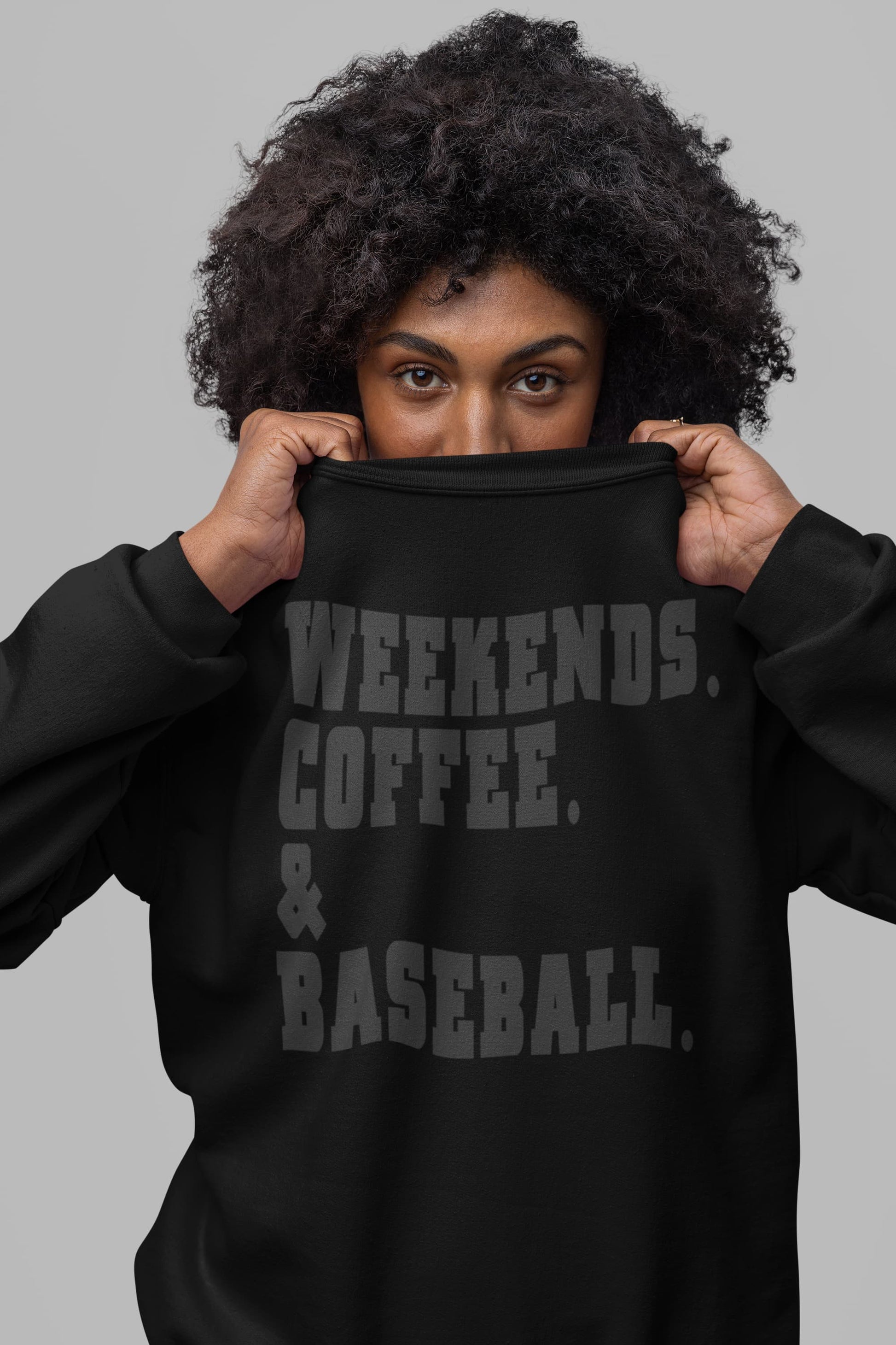 Close up of black weekends coffee baseball sweatshirt with stacked varsity text worn by woman
